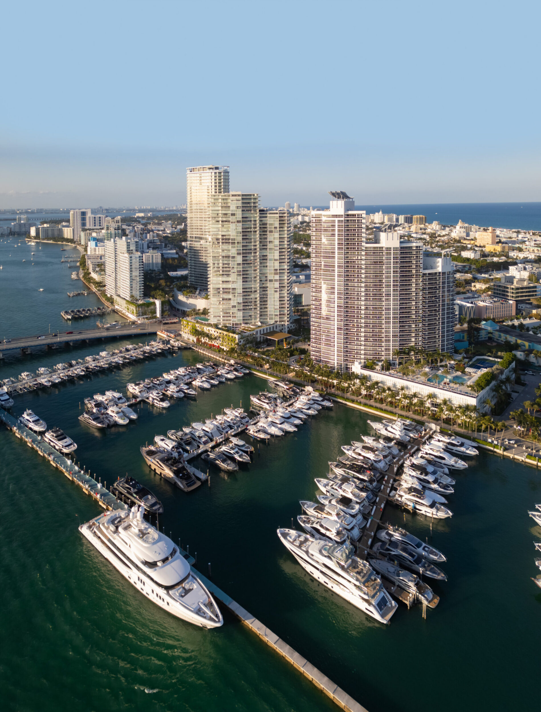 Aerial view of Miami beach with luxury yachts and tropical skyline. Coastline Miami waterfront. Sailboats and yachts in a calm marina and turquoise ocean. Luxury cruise ship.